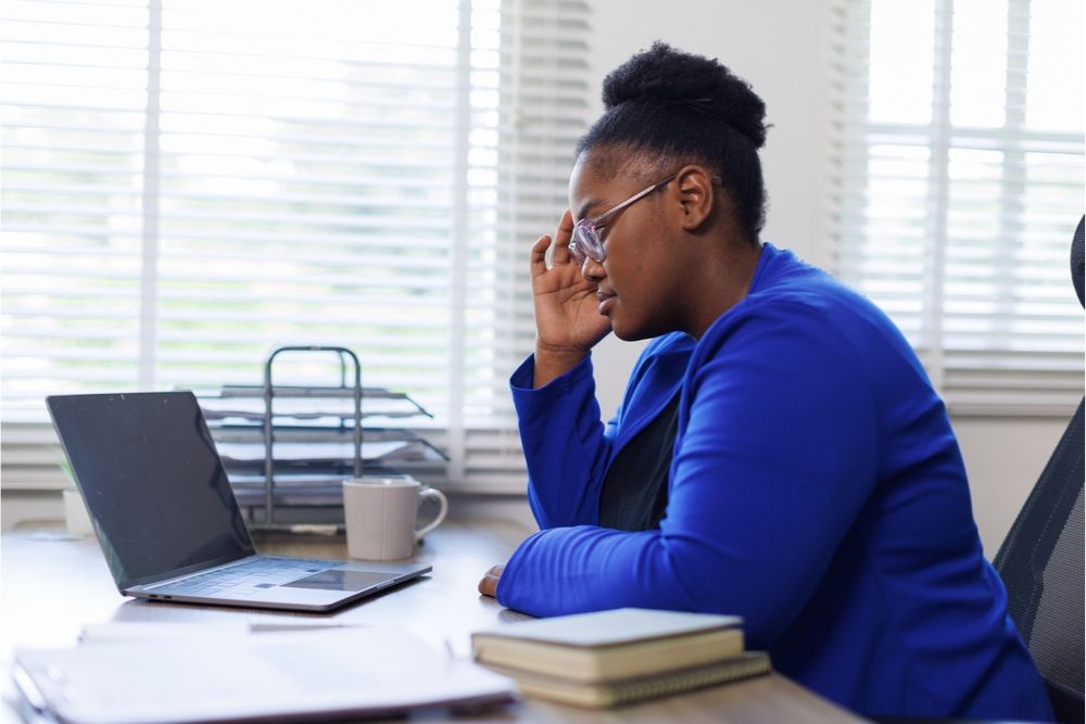 black women sat at laptop in deep thought